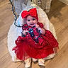 baby, child, red_dress, headband, bow, christmas_lights, holiday, smiling, indoor, flooring, wooden_floor, decorations, christmas_tree, festive, cushion, white_fur, cute, happy, portrait, toddler