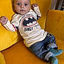 James a rejoint le concours — aidez-le/la à gagner de superbes lots ! baby, child, yellow_couch, batman_shirt, jeans, blue_socks, indoor, cute, portrait, smiling, person, infant, cozy, furniture, apparel, casual, relaxed, happy, small_hands, bright