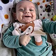 James a rejoint le concours — aidez-le/la à gagner de superbes lots ! baby, smiling, infant, child, cute, face, clothing, blanket, toy, soft_toy, polka_dot, happy, lying_down, indoors, portrait, cute_outfit, baby_garment, hand, head, cozy