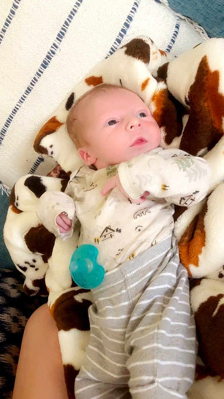 Eli Allen joined the competition — help win amazing prizes! baby, blanket, child, clothing, comfort, cow_print, cozy, cute, face, hand, indoors, infant, lying_down, newborn, onesie, pacifier, person, resting, soft_texture, striped_pants