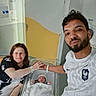 baby, bassinet, beard, bedroom, blanket, clothing, couple, family, happy, hat, holding_hands, hospital, indoor, man, newborn, parenthood, person, rest, smile, woman