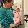 Myriam participe au concours pour gagner de l'argent avec cette photo : elderly_woman, baby, newborn, indoor, holding, teal_sweater, pink_onesie, glasses, woman, person, infant, family, care, love, portrait, warmth, skin, room, casual, comfort