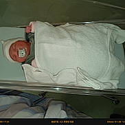 Myriam a rejoint le concours — aidez-le/la à gagner de superbes lots ! baby, baby_care, bed, blanket, clothing, cute, face, hat, healthcare, hospital, hospital_bassinet, indoor, infant, newborn, pacifier, person, resting, sleeping, swaddled, white_towel