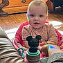 baby, child, pink_baby_seat, toy, mickey_mouse, rainbow_reflection, hand, wooden_floor, wooden_drawer, leather_sofa, indoor, happy, smiling, infant, person, cute, playful, holding_hand, home, cozy