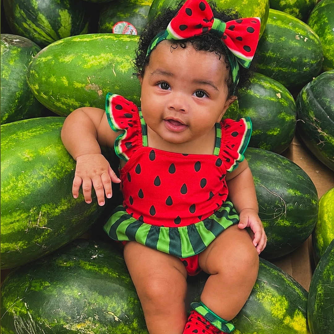 Chosyn is registered to the contest to win money with this photo: baby, child, infant, watermelon, fruit, watermelon_costume, red_outfit, green_outfit, bow, headband, smiling, sitting, portrait, indoor, market, produce, groceries, fashion, colorful, cute
