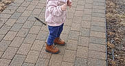 Serenity is registered to the contest to win money with this photo: blonde_hair, boots, brick_path, candid, car_wheel, child, cool_weather, curious_expression, girl, grass, outdoors, pavement, pink_jacket, profile_view, sidewalk, small_shoes, standing, stick, toddler, young_child