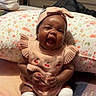 Kamoria is registered to the contest to win money with this photo: baby, child, infant, pink_outfit, headband, knitted_clothing, white_socks, floral_pillow, blanket, yawning, happy, indoors, furniture, dresser, person, cute, smiling, seated, cozy, home