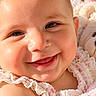 baby, child, infant, smiling, happy, portrait, close_up, face, eyes, floral_clothing, pink, teddy_bear, stuffed_animal, blanket, soft_lighting, indoor, warm_tones, lying_down, adorable, photography