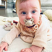 Hilda participe au concours pour gagner de l'argent avec cette photo : baby, pacifier, crawling, blanket, plush_toy, indoor, living_room, child, curious, soft_lighting, cozy, furniture, carpet, clothing, person, face, hand, blue_eyes, cute, infant