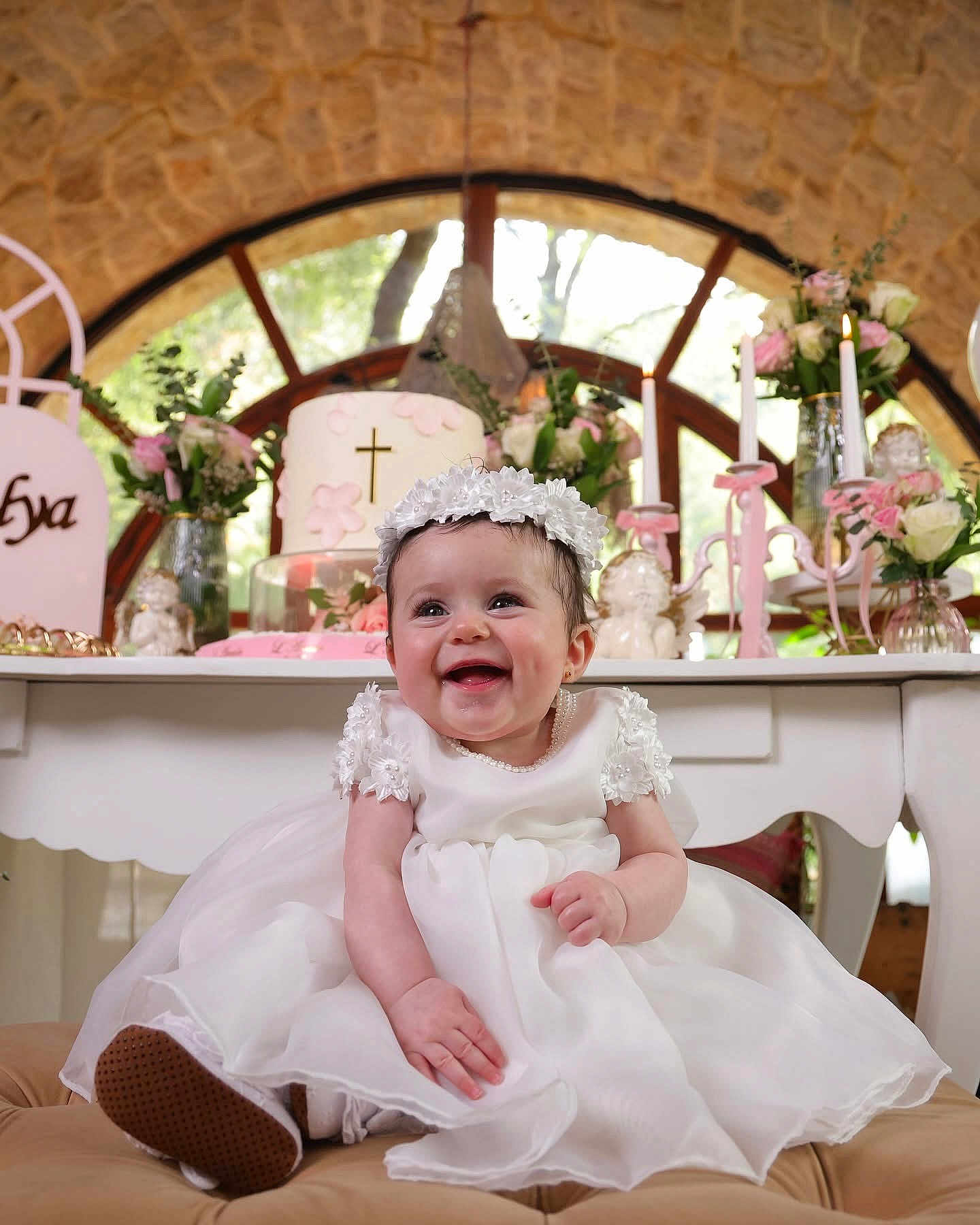 Talya participe au concours pour gagner de l'argent avec cette photo : baby, smiling, white_dress, flower_headband, candle, cake, cross, flowers, celebration, table, decorations, happy, indoors, portrait, child, event, cute, joyful, party, ceremony