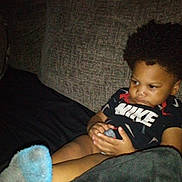 Tristan is registered to the contest to win money with this photo: black_clothing, blanket, casual, child, clothing, couch, expression, face, furniture, hair, home, indoor, legs, nike, person, portrait, relaxing, sitting, socks, toddler