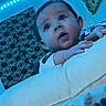 baby, infant, face, blue_light, led_lights, cushion, blanket, indoor, child, eyes, hands, pattern, wall_art, nursery, person, portrait, sleepwear, expression, curious, head