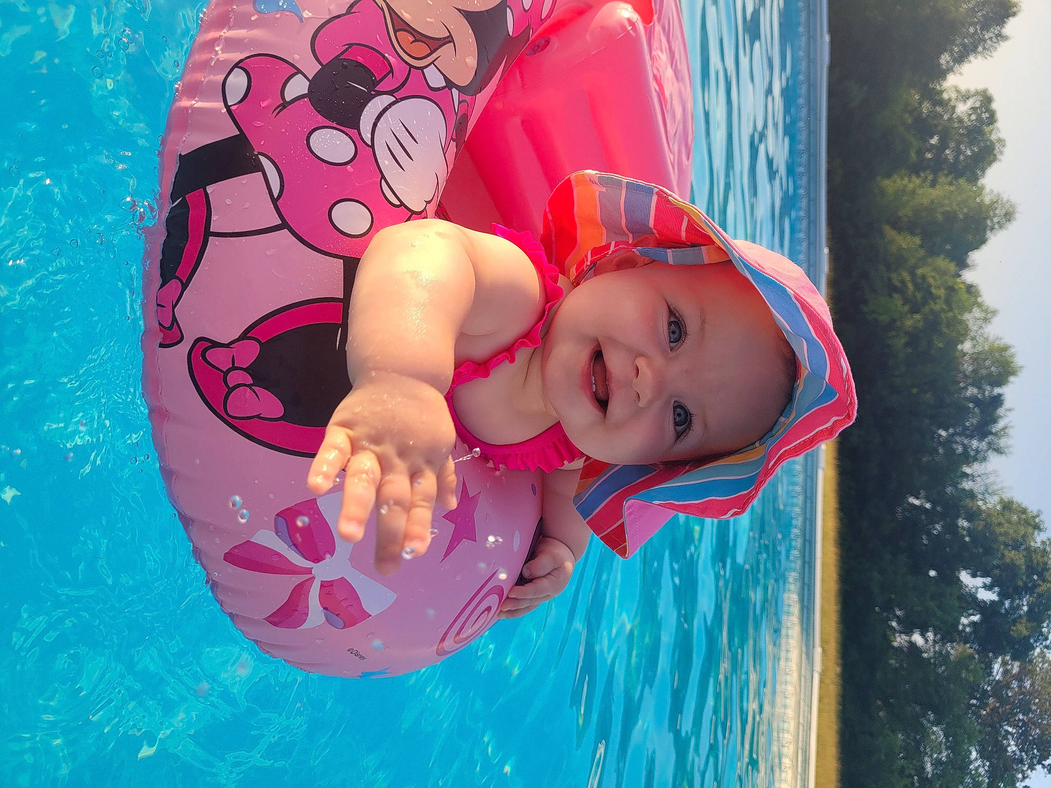 Shaylee is registered to the contest to win money with this photo: baby, baby_float, baby_products, baby_toddler_clothing, child, fun, happy, hat, headwear, joy, leisure, magenta, people_in_nature, person, pink, plant, recreation, smile, sun_hat, swimming_pool