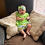baby, child, smiling, green_clothing, headband, pillow, quilted_pillow, armchair, indoor, window, natural_light, happy, cute, infant, sitting, fabric, home, cozy, comfortable, portrait
