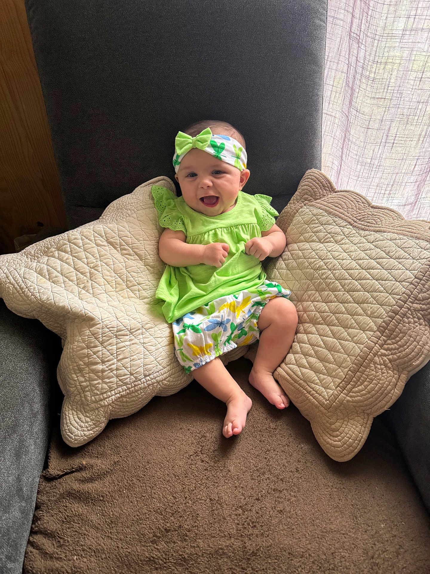 Juliana a rejoint le concours — aidez-le/la à gagner de superbes lots ! baby, child, smiling, green_clothing, headband, pillow, quilted_pillow, armchair, indoor, window, natural_light, happy, cute, infant, sitting, fabric, home, cozy, comfortable, portrait