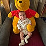 Juliana participe au concours pour gagner de l'argent avec cette photo : baby, child, stuffed_toy, winnie_the_pooh, plush, chair, onesie, socks, red, yellow, face, person, indoor, furniture, blanket, curtain, bookshelf, wood, cozy, smiling