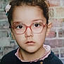 Maryam participe au concours pour gagner de l'argent avec cette photo : brick_wall, casual_clothing, child, close_up, curly_hair, eyewear, face, girl, glasses, hair_bow, headshot, indoor, looking_at_camera, person, pink_collar, portrait, serious_expression, studio_lighting, sweater, young