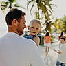 child, toddler, man, family, beach, palm_trees, sunlight, outdoor, summer, vacation, casual_clothing, people, sand, nature, portrait, smile, happy, walking, holding, daylight