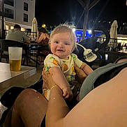 Thomas joined the competition — help win amazing prizes! baby, child, person, adult, night, outdoor, dining, restaurant, table, chair, drink, beverage, stroller, clothing, smile, happy, light, people, arm, face