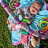 baby, smiling, blue_blanket, outdoor, grass, toys, headband, baby_playmat, colorful, infant, happy, cute, stuffed_animal, child, playtime, person, nature, baby_clothes, soft_toys, relaxing