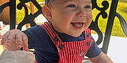 Waylon is registered to the contest to win money with this photo: baby, child, smiling, happy, outdoor, chair, cushion, headband, usa, red_striped_overalls, blue_shirt, sunlight, grass, face, person, portrait, celebration, festive, tongue_out, cute