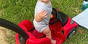 Waylon is registered to the contest to win money with this photo: barefoot, blanket, bottle, child, daylight, expression, fun, gesture, grass, gray_shirt, lawn, outdoor, person, playing, red, sidewalk, summer, toddler, toy_car, young