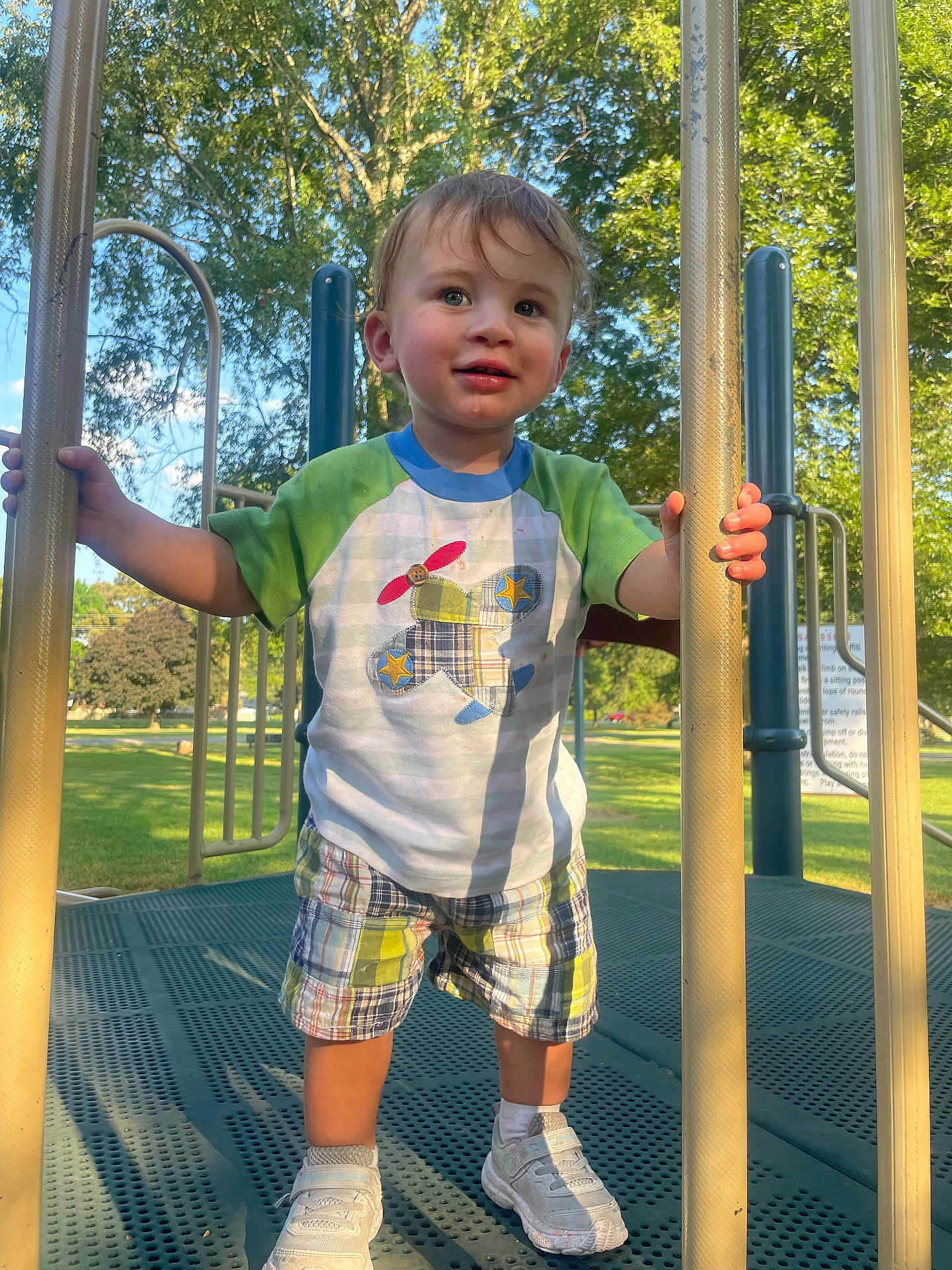 Olliemore joined the competition — help win amazing prizes! toddler, child, playground, outdoor, park, trees, sunlight, clothing, shorts, shirt, sneakers, smile, happy, play, summer, daytime, person, metal_bars, greenery, fun