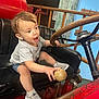 Olliemore is registered to the contest to win money with this photo: toddler, child, vintage_car, steering_wheel, gear_shift, sneakers, shorts, gray_tshirt, black_seat, red_vehicle, wooden_knob, indoor, curious, playful, young_child, person, seat, hand, expression, footwear