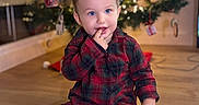Cayden a rejoint le concours — aidez-le/la à gagner de superbes lots ! toddler, child, pajamas, plaid, floor, wooden_floor, christmas_tree, ornaments, holiday, indoors, decorations, festive, lights, smiling, cute, person, sitting, baby, cozy, finger_in_mouth