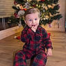 toddler, child, pajamas, plaid, floor, wooden_floor, christmas_tree, ornaments, holiday, indoors, decorations, festive, lights, smiling, cute, person, sitting, baby, cozy, finger_in_mouth