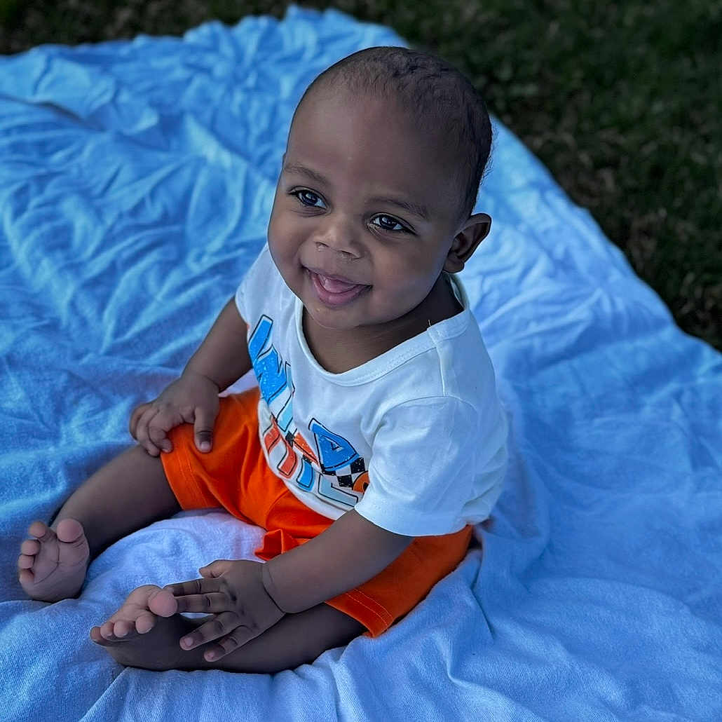 Kyier joined the competition — help win amazing prizes! baby, child, smiling, sitting, outdoor, blanket, white_shirt, orange_shorts, grass, happy, cute, portrait, infant, young_child, barefoot, daylight, playful, casual_clothing, skin, head