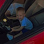 toddler, child, car, steering_wheel, red_car, white_dress, seat, seatbelt, smile, playing, interior, vehicle, happy, person, footwear, sneakers, daylight, window, hand, fun