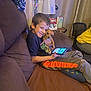 Cookie is registered to the contest to win money with this photo: boy, dog, couch, tablet, smiling, indoor, lamp, holiday_cards, curtain, brown_couch, child, happy, pet, technology, casual_clothing, home, small_dog, cozy, seated, living_room