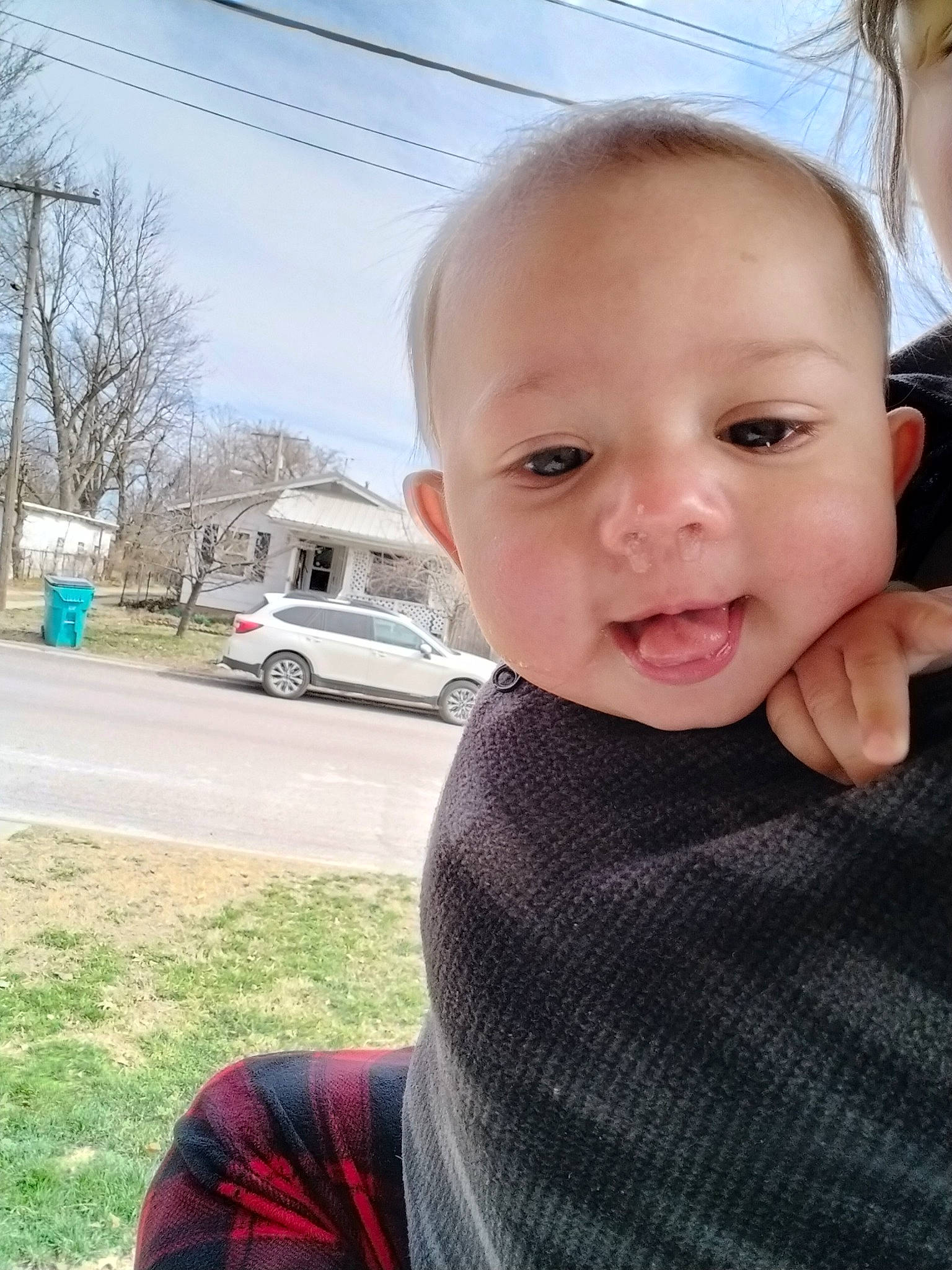 Oliver is registered to the contest to win money with this photo: automotive_tire, baby_toddler_clothing, car, cheek, chin, eyelash, gesture, grass, hair, happy, lip, nose, person, plant, skin, sky, tire, toddler, tree, wheel