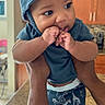 Bentley is registered to the contest to win money with this photo: baby, child, hands, blue_hat, blue_shirt, shorts, kitchen, countertop, cabinet, person, indoor, cute, infant, curious, playful, skin, face, expression, holding, nibbling