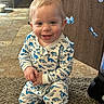 toddler, child, smiling, dinosaur_pajamas, indoor, carpet, kneeling, blue_butterflies, wooden_background, happy, cute, young_child, floor_tiles, baby, face, person, playful, home, pajamas, decorations