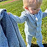 toddler, child, grass, outdoor, field, sunny, daylight, grey_clothing, pajamas, person, holding, sweatshirt, nature, suburban, houses, curious, young_child, blond_hair, standing, casual