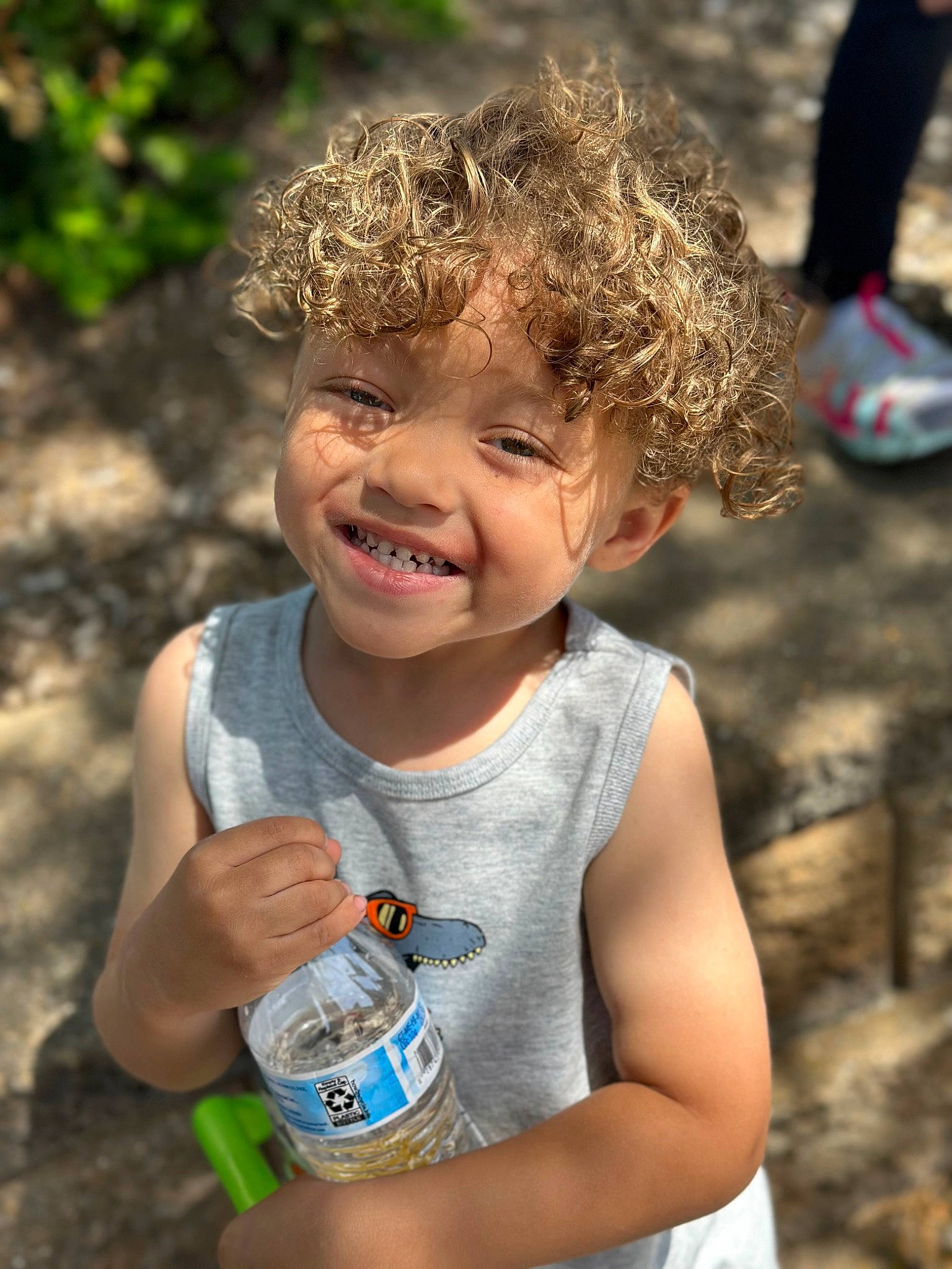 Romello is registered to the contest to win money with this photo: child, facial_expression, fun, gesture, grass, hairstyle, hand, happy, joint, joy, leisure, organ, people_in_nature, person, photograph, plastic_bottle, skin, smile, summer, sunlight