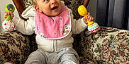 Florentin a rejoint le concours — aidez-le/la à gagner de superbes lots ! baby, child, armchair, rattle, pink_bib, curly_hair, smiling, happy, indoor, clothing, sweater, pants, footed_pants, furniture, floral_pattern, vintage, person, portrait, cute, seated