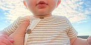 Millie joined the competition — help win amazing prizes! baby, child, person, sky, clouds, outdoor, striped_shirt, hand, holding, face, cute, infant, portrait, sunlight, blue_sky, expression, casual_clothing, young_child, daytime, human