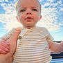 baby, child, person, sky, clouds, outdoor, striped_shirt, hand, holding, face, cute, infant, portrait, sunlight, blue_sky, expression, casual_clothing, young_child, daytime, human