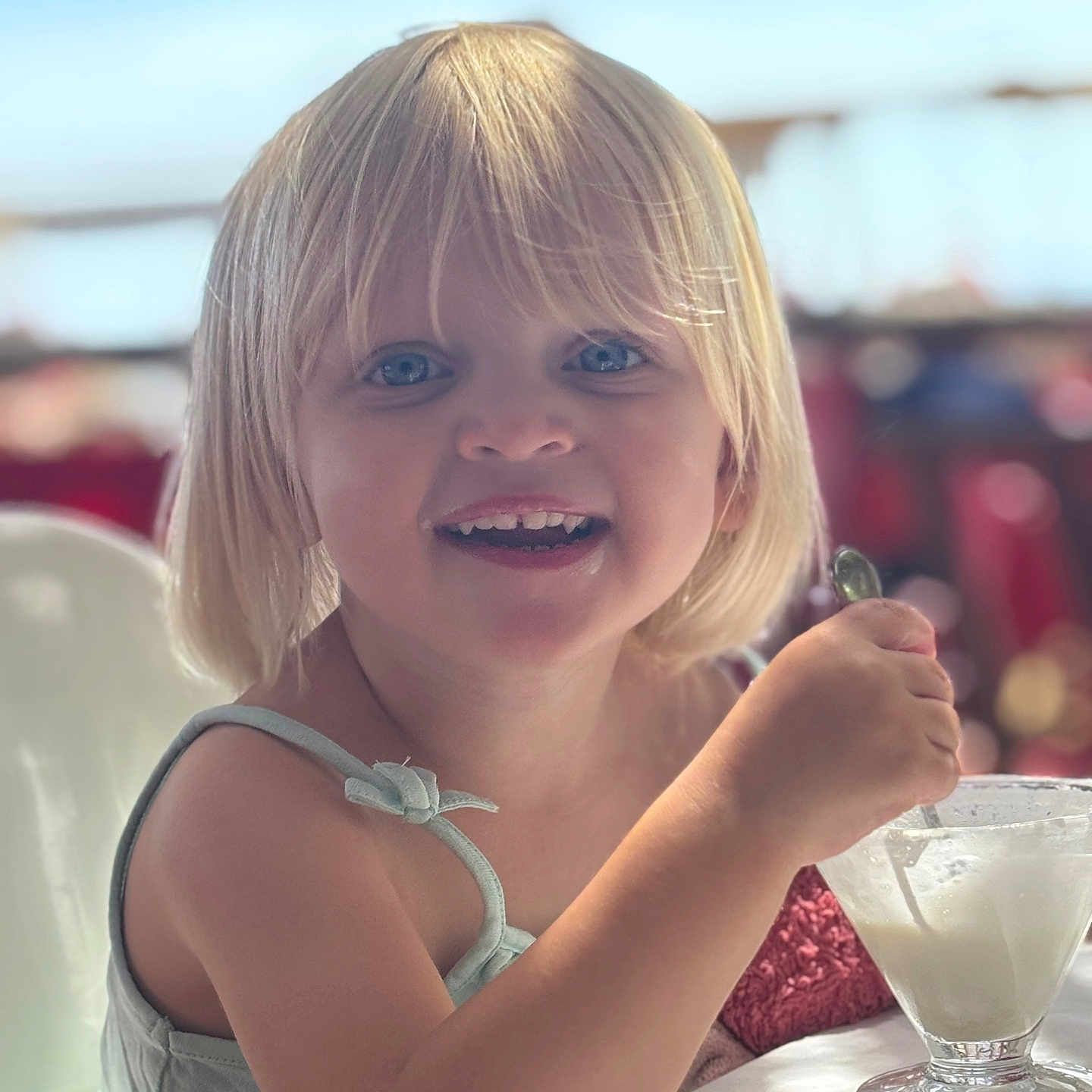 Julia participe au concours pour gagner de l'argent avec cette photo : background_bokeh, bangs, blonde_hair, blue_eyes, candid, child, close_up, dessert, dining_table, family_restaurant, glass_cup, happy, high_chair, ice_cream, portrait, sleeveless_top, smile, soft_lighting, spoon, toddler