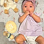 Liara is registered to the contest to win money with this photo: baby, infant, headband, socks, plush_toy, wooden_rattle, milestone_plaque, blanket, bunny_pattern, lying_down, purple_clothing, cute, hand_in_mouth, child, soft_toy, indoor, closeup, adorable, newborn, portrait