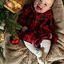 baby, smiling, red_dress, plaid, white_tights, blanket, christmas_tree, ornaments, holiday, festive, cozy, infant, happy, face, child, indoors, soft_texture, cute, celebration, seasonal