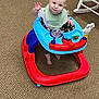Grady is registered to the contest to win money with this photo: baby, bib, carpet, child, clothing, colorful, cute, expression, floor, foot, hand, indoor, person, play, rocking_chair, seat, smile, toy, walker, young