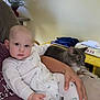 Grady is registered to the contest to win money with this photo: animal, arm, baby, cat, child, clothing, couch, face, furniture, gray_cat, hand, indoor, notebooks, pajamas, papers, person, pet, portrait, relaxing, table