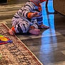 baby, carpet, child, crawling, cute, door, floor, foot, furniture, hand, home, indoor, infant, living_room, pacifier, pajamas, person, rug, striped_clothing, wooden_floor