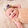 baby, infant, smiling, face, blanket, floral_headband, ruffled_dress, soft_texture, portrait, rosy_cheeks, lying_down, happy, newborn, adorable, closeup, studio_photography, cute, eye_contact, skin, person