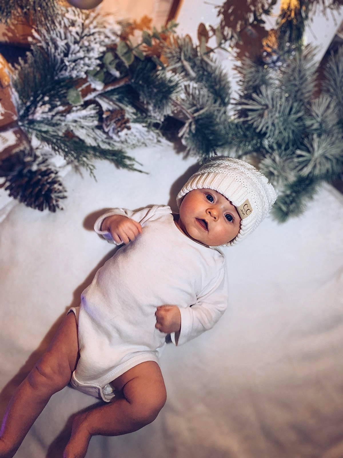 Lylah is registered to the contest to win money with this photo: baby_toddler_clothing, christmas_decoration, christmas_ornament, event, eye, flash_photography, happy, hat, headwear, holiday, human_body, human_leg, leg, ornament, people_in_nature, person, plant, thigh, toddler, tree