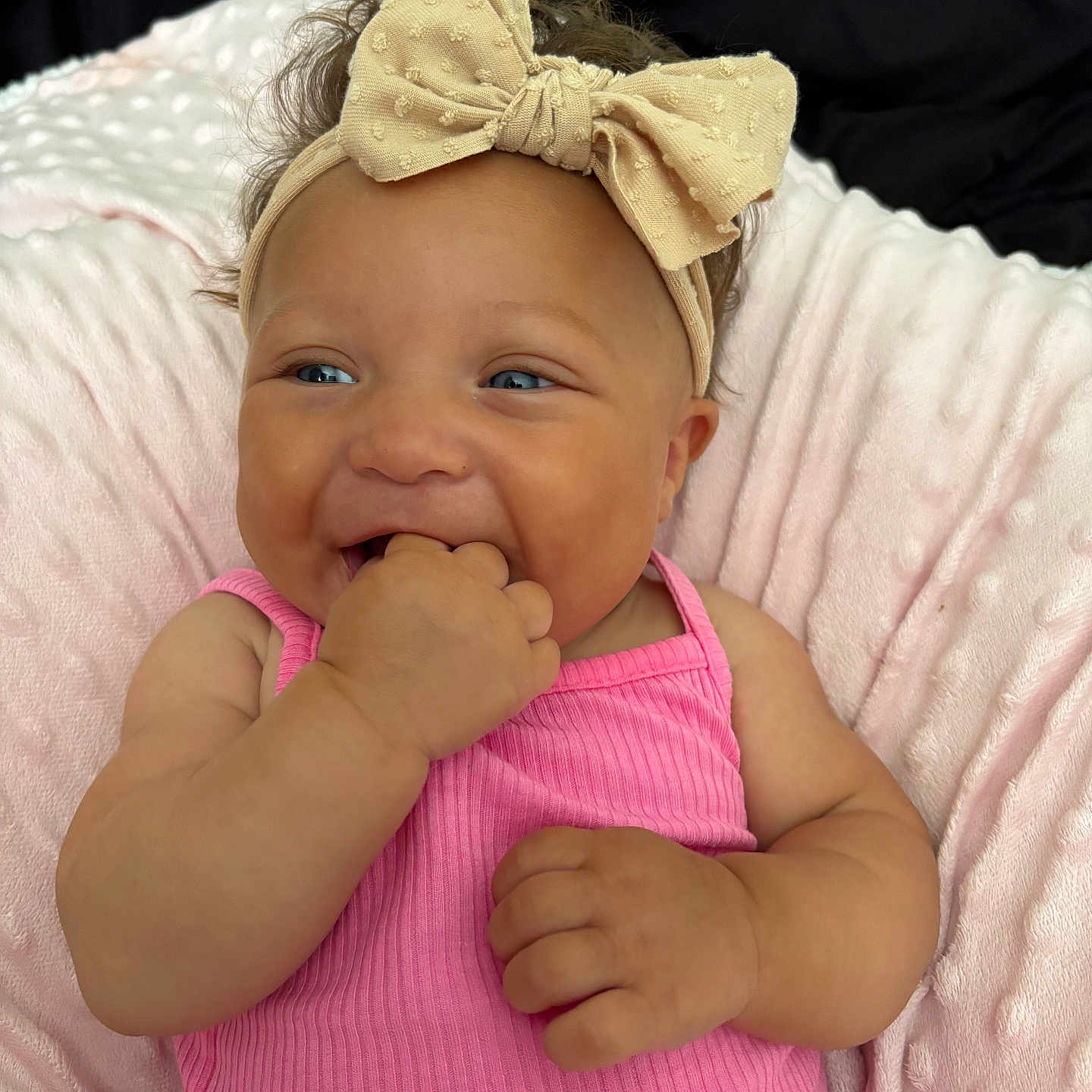 Eilena Lea is registered to the contest to win money with this photo: baby, blanket, bow, child, closeup, cute, fingers, hand_in_mouth, happy, headband, indoors, infant, lying_down, person, pink_clothing, portrait, skin, smiling, soft_texture, toddler